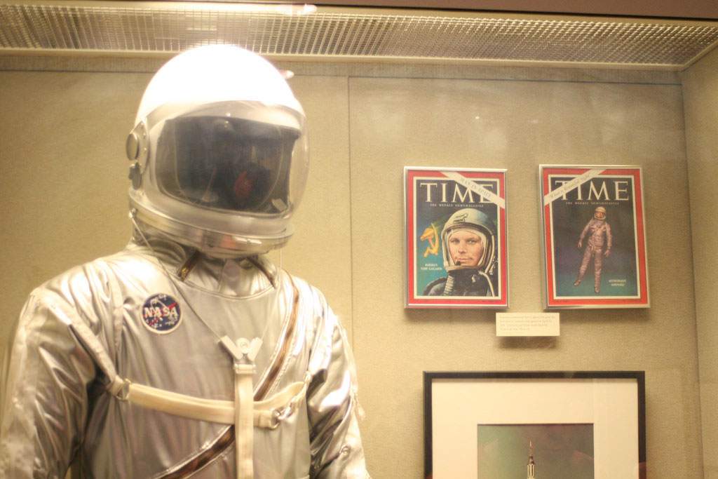 A museum display of John Glenn's spacesuit and magazine covers featuring him