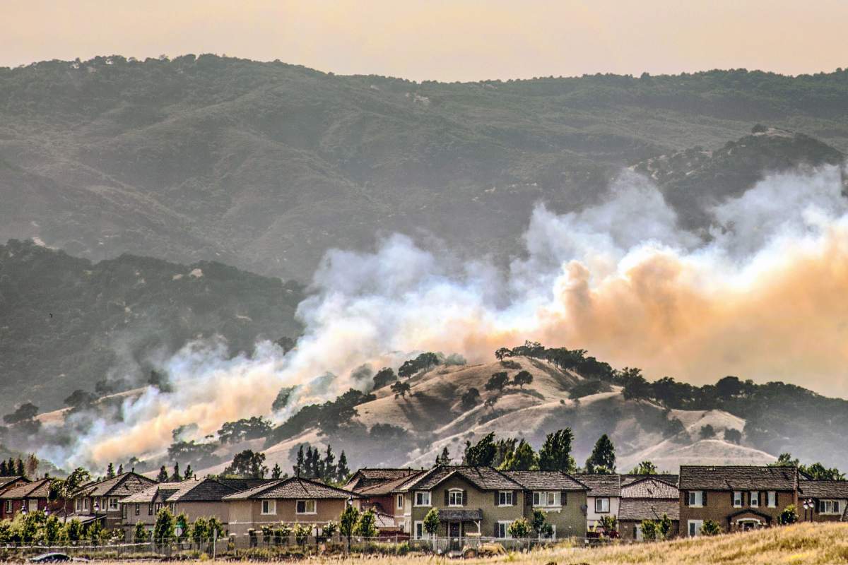 Smoke and mountains in the background, a neighborhood in the foreground.