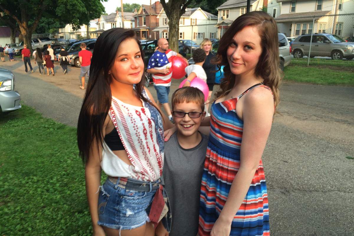 Two teenage girls with a much shorter boy between them