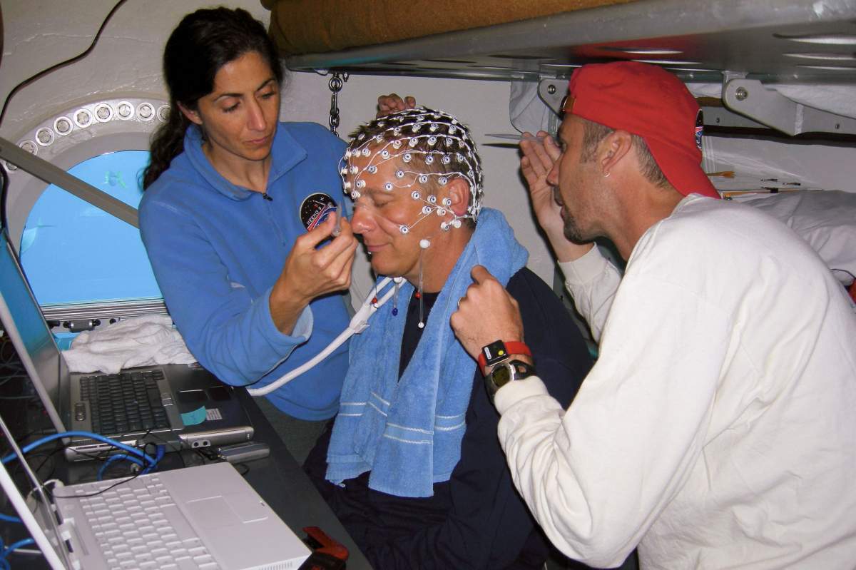 two people setting up an electroencephalogram cap on another person
