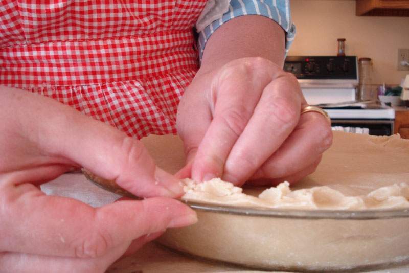 This person is in the middle of fluting the pie crust. You flute pie crust not just because it looks good, but also as a structural support  during the baking process. (Julie Falk, Flickr)
