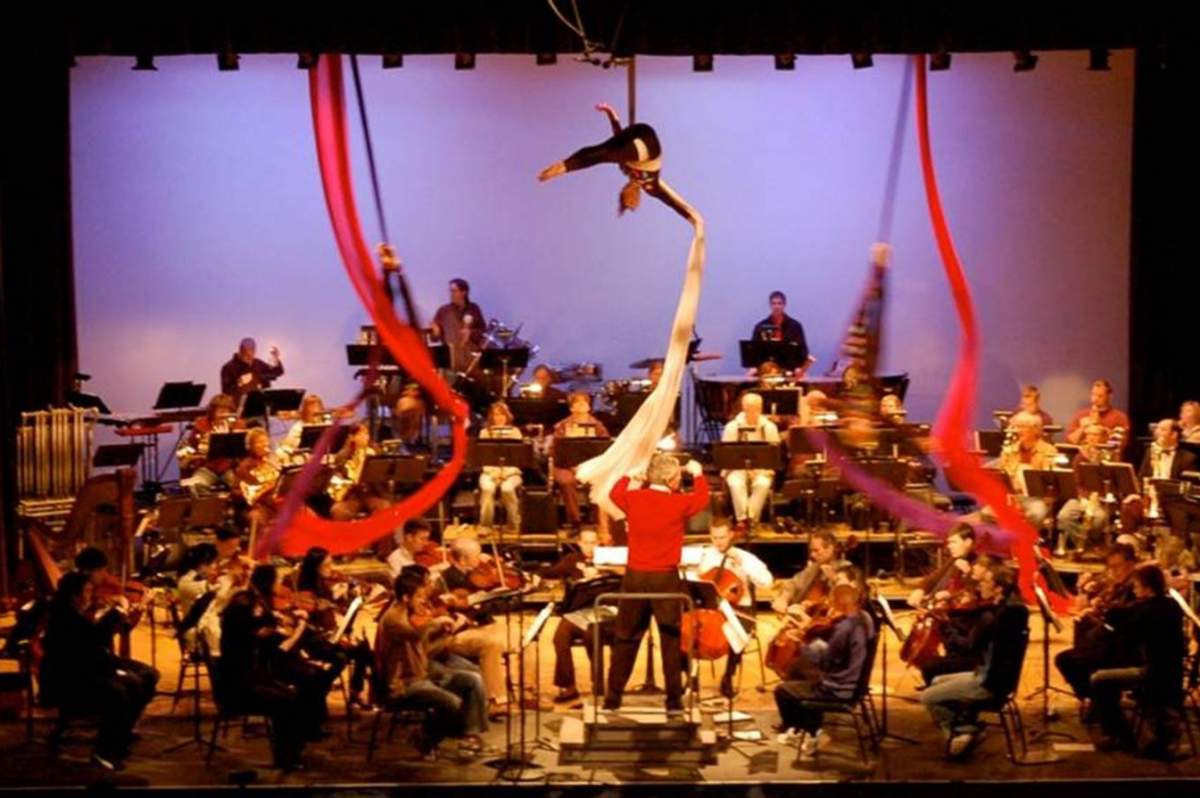 aerilists swing from long ribbons over a symphony orchestra