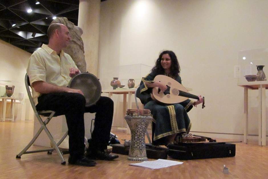 A man and woman smile at each other while playing Middle Eastern music in an Art Gallery