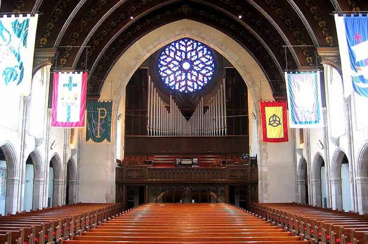 A church sanctuary with banners, an organ and a rose window