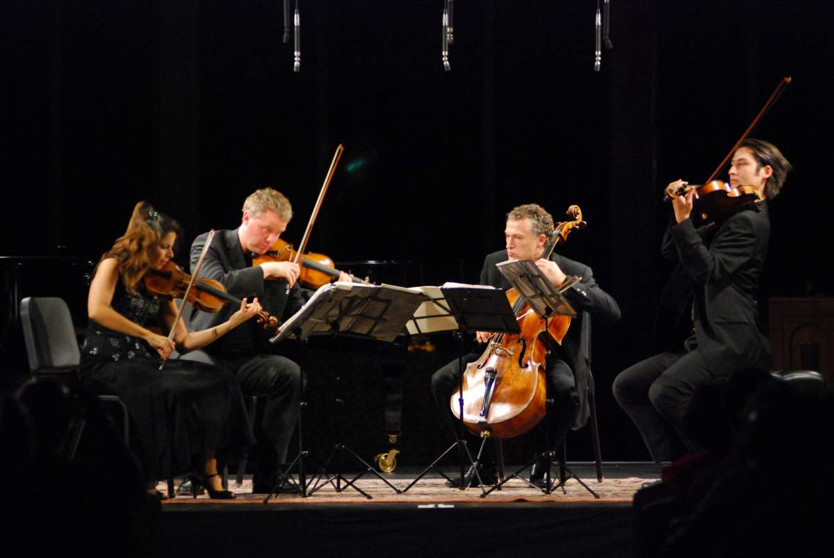 a string quartet performs in front of a black backdrop.