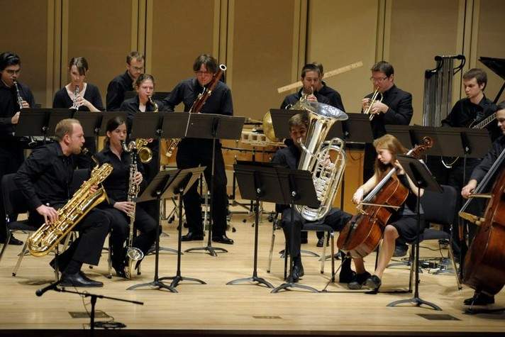 An ensemble of saxophones, strings and other instruments perform on stage