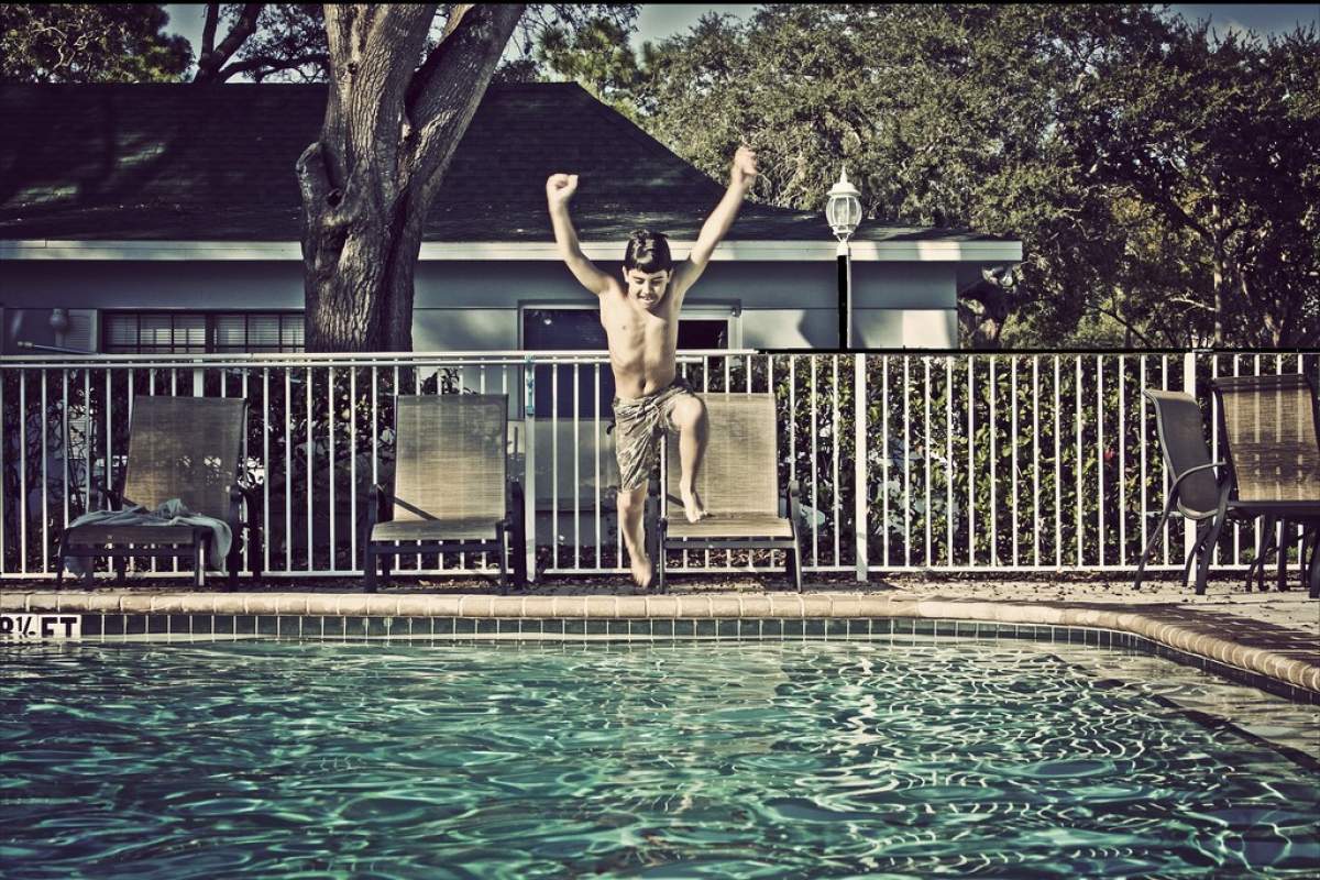 a boy jumps into a pool