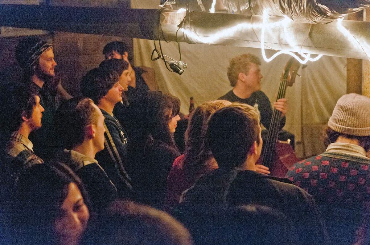 crowd listening to a live band perform in a basement