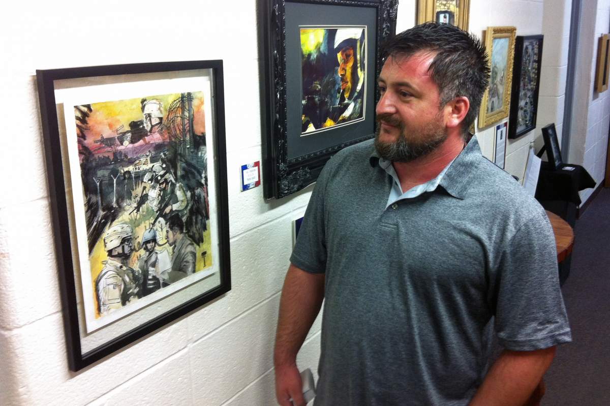veteran artist mark smith standing next to his paintings