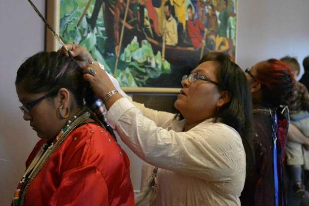 Mother adjusts daughter's headdress in preparation for powwow.