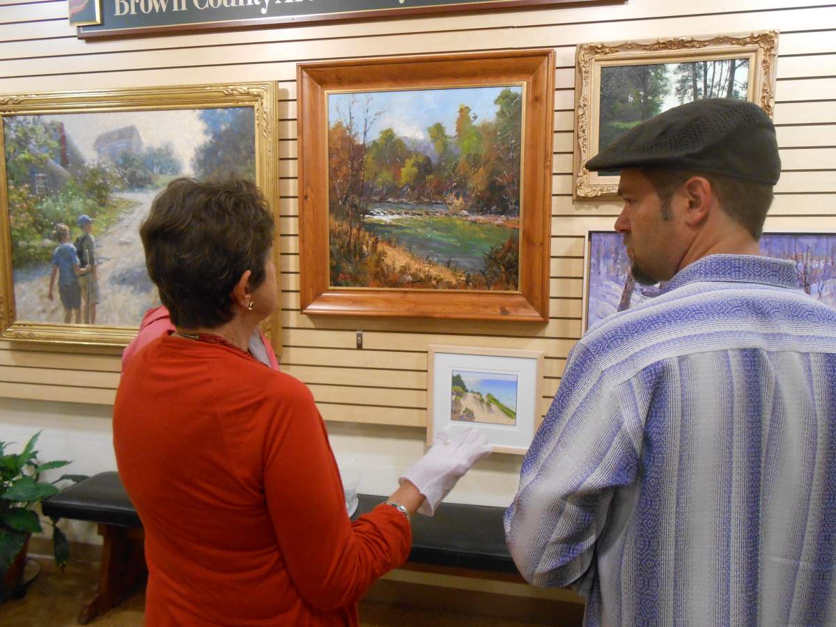 two people talking in front of paintings hung on the wall