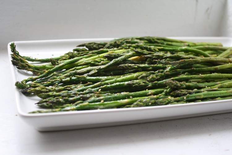 Two pounds of roasted asparagus on a rectangular white plate