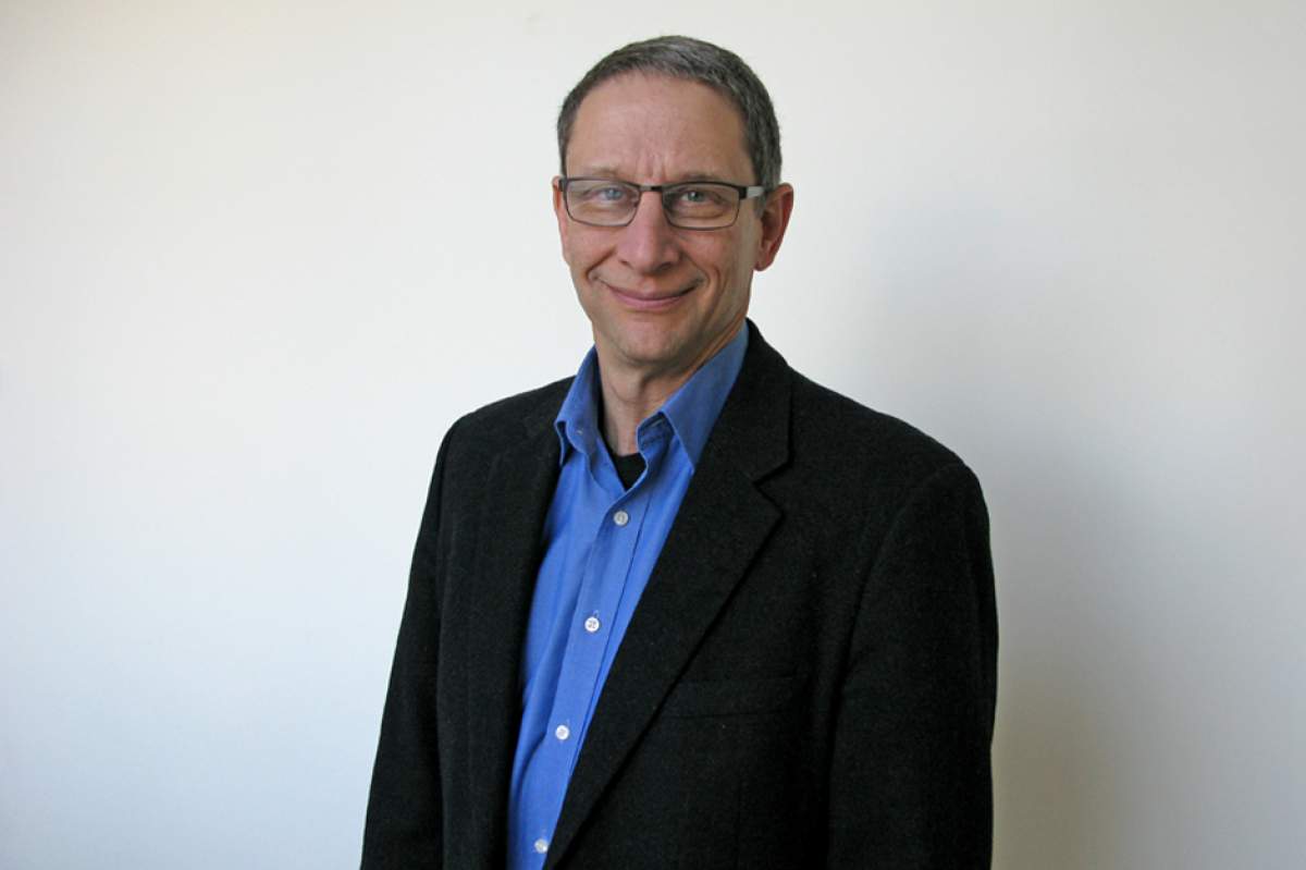 David Finkel in blue shirt open at the neck and black blazer, glasses