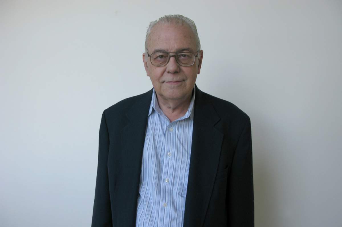 David Morrison in glasses, dark suit jacket without tie, looking into camera with serious expression