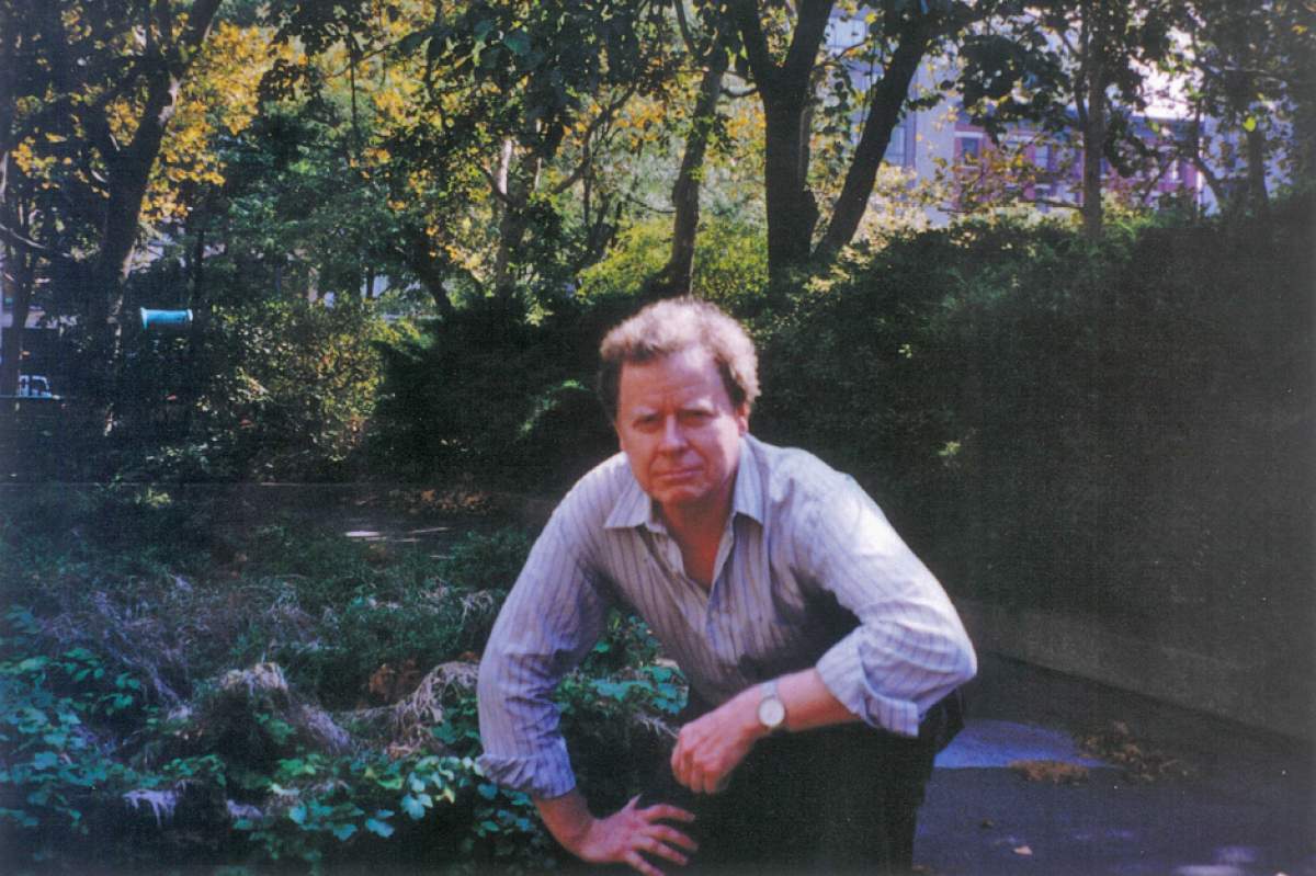 Larry Lockridge outside, in an open-necked shirt, crouching