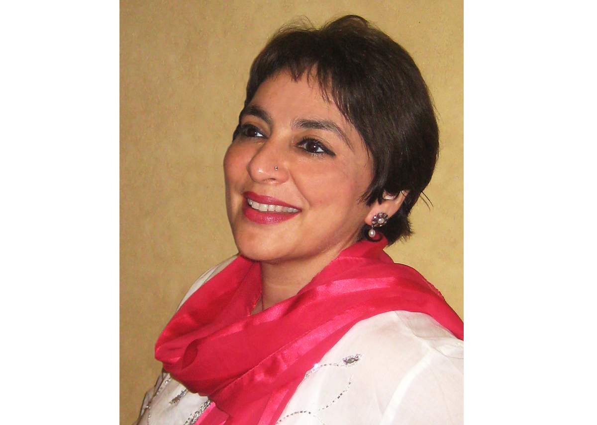 Shauna Singh Baldwin smiling, wearing white top and red scarf