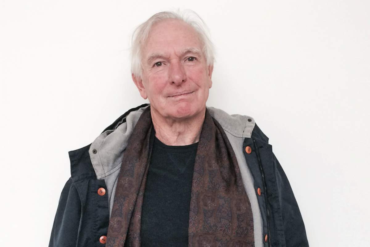 Peter Weir, white-haired, head tilted a little, in parka over black shirt and brown scarf
