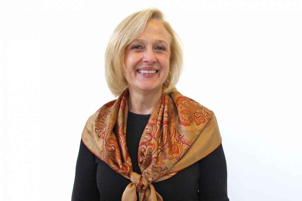 Paula Kerger in black top and scarf draped over shoulders, smiling.
