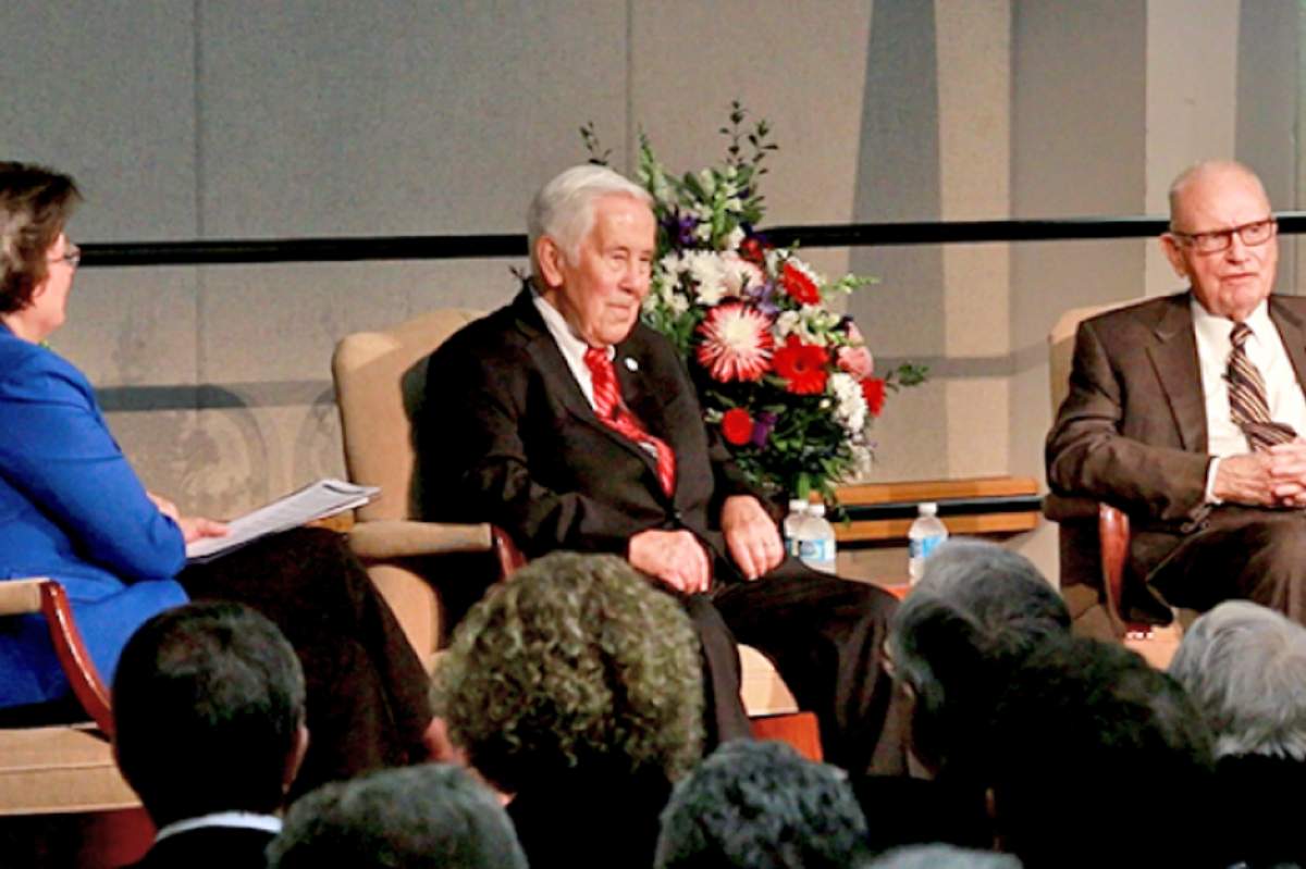 USI President Dr. Linda L.M. Bennett, Senator Richard G. Lugar, and former Congressman Lee H. Hamilton seated on stage with heads of audience members in foreground.