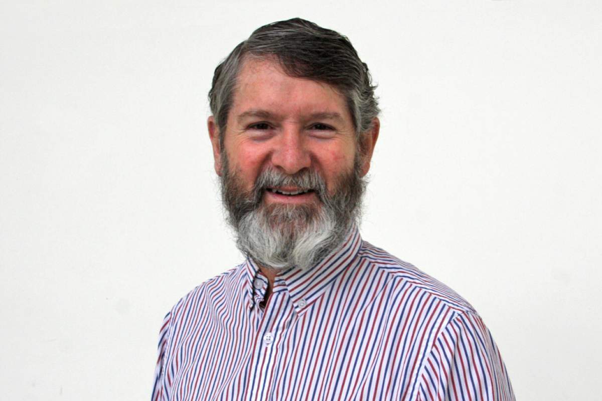 Graham Hopkins, graying beard, smiling, in pinstriped shirt.