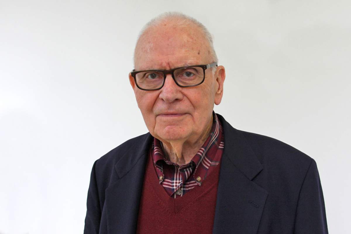 Lee Hamilton wearing glasses, dressed in red checked shirt, maroon sweater, and black suit jacket.