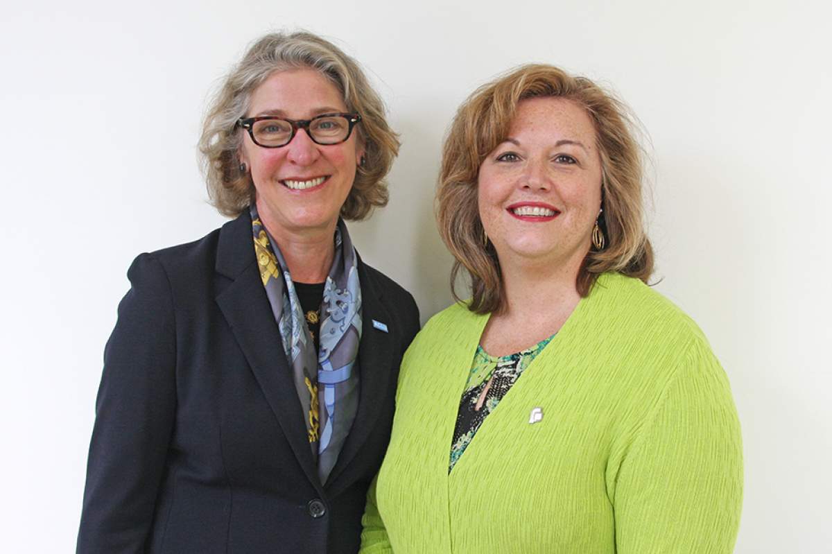Jane Henegar in navy blazer, colorful silk scarf, and "ACLU" pin; Christie Gillespie in lime green sweater and pin with Planned Parenthood logo.