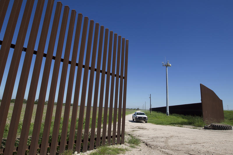 A white pickup truck crosses a break in the fence along the US' southern border.