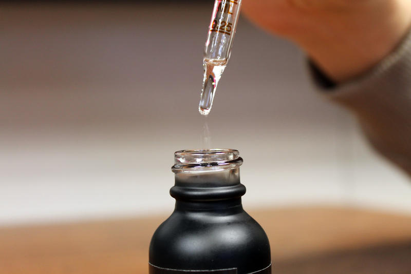 An eye dropper drops liquid into a bottle