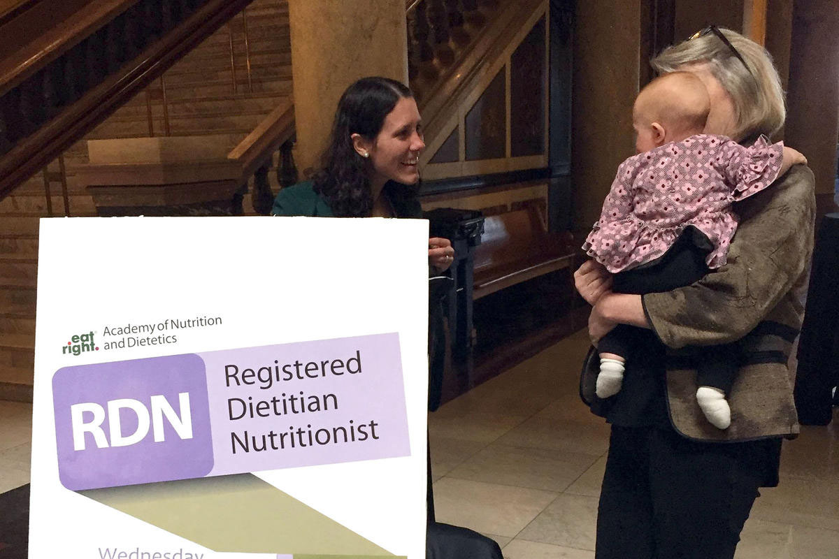 A person holding a baby next to a sign that says registered dietitian nutritionist