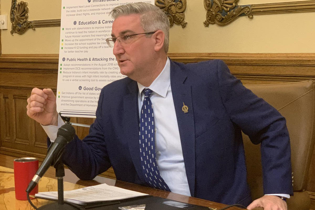 eric holcomb in a blue suit seated at a desk