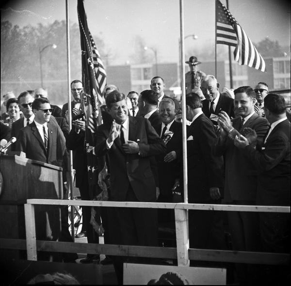 John Fitzgerald Kennedy to left of pole at center, and Birch Bayh to right of pole at center.