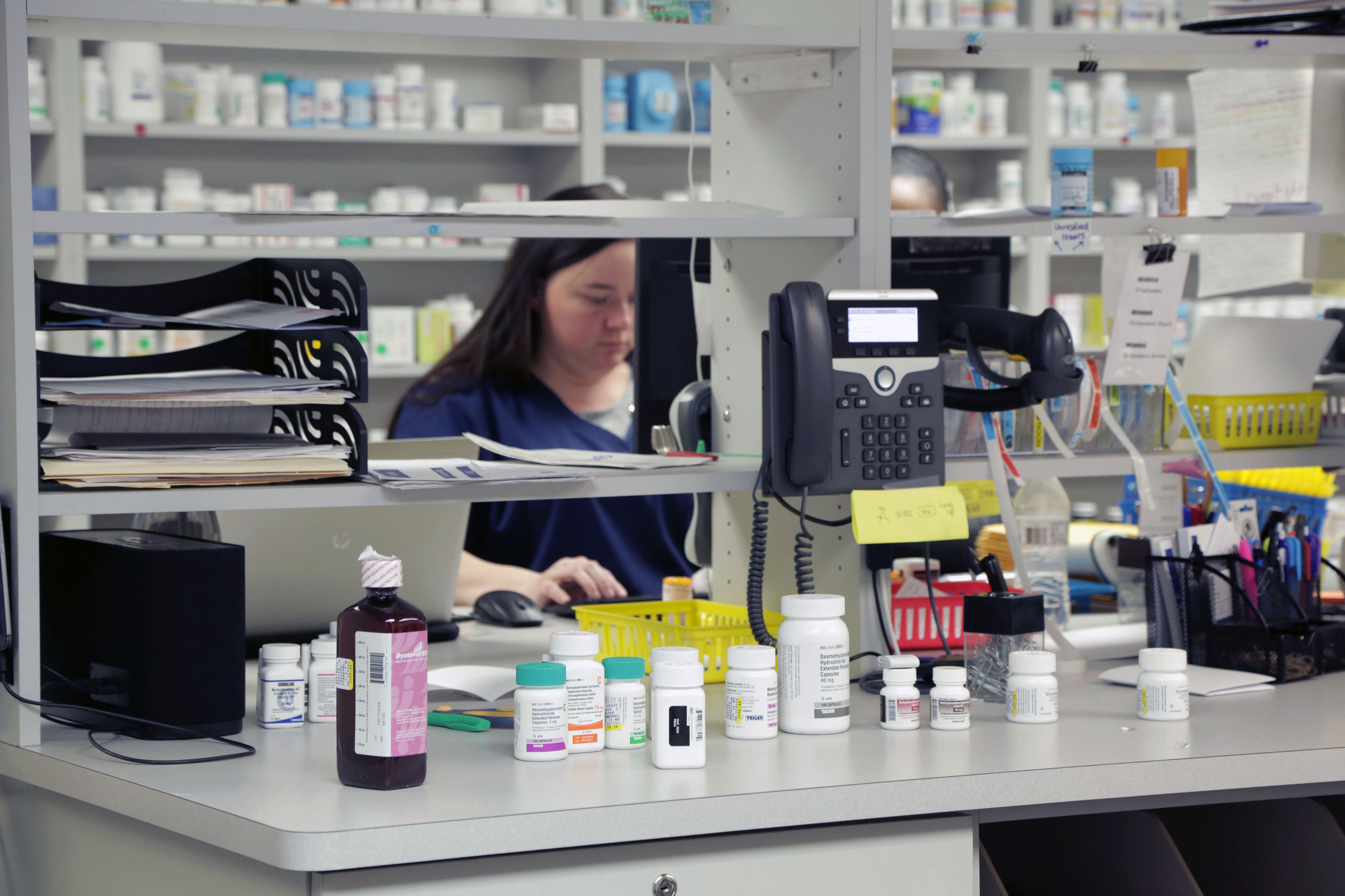 A person preparing medications at a pharmacy counter