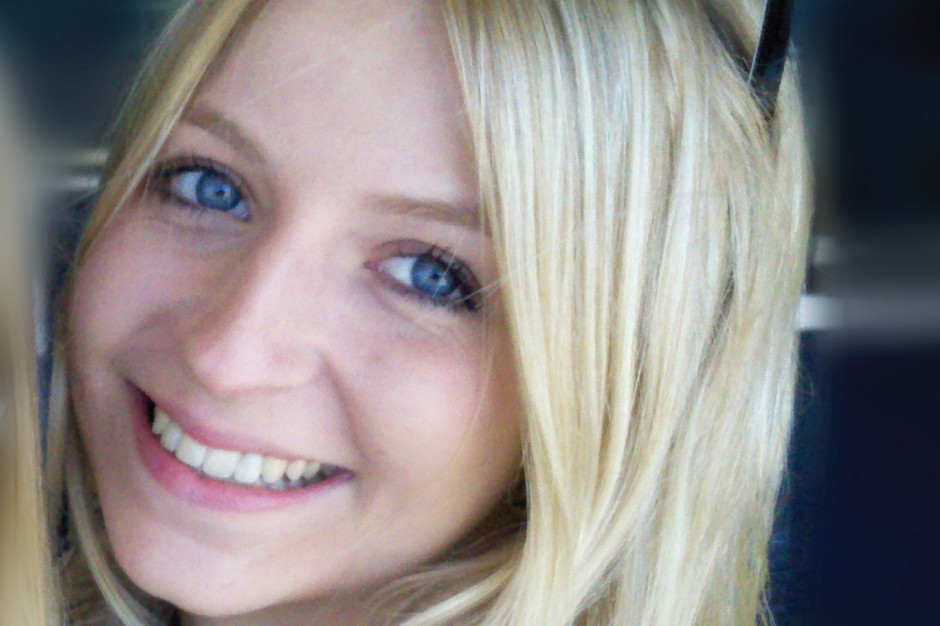 A young blonde woman with blue eyes smiling