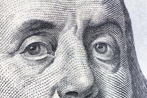 A closeup of Benjamin Franklin's eyes as popularly reprinted on currency
