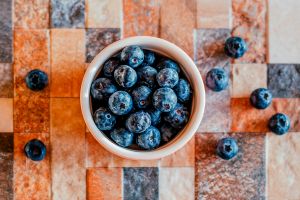 Blueberries in a white bowl on a wood checkered table