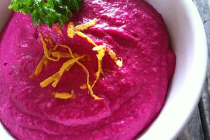 bright pink dip in a white bowl with thin yellow strips of lemon zest and parsley accents