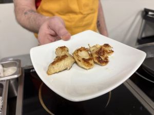 hands holding a white plate with synthetic chicken slices atop