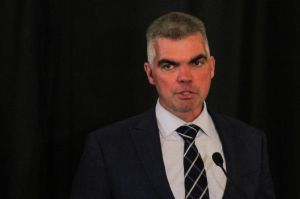 man in suit with gray hair talking at a microphone