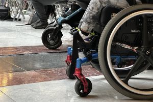 A close up of a child's wheelchair at the Indiana Statehouse. Their front wheel supports are red and blue. 