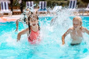 Children laughing while splashing water in swimming pool