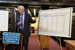 Representative Ed Delaney holding a microphone in front of a whiteboard