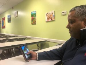 Attorney FritzGerald Tondreau, holding a phone, shows intimidating videos of gang hostages and enemies being killed or beaten in Haiti