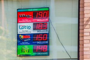 A board hanging in a window displays lottery jackpot amounts.