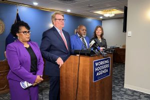 House Democratic leaders stand next to each other in a line in front of a lectern.