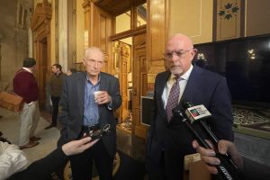 Jeff Thompson and Travis Holdman speak to each other while seated in a committee room