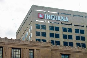 A brown building with an orange polygon with IN and outside of the polygon INDIANA spelled in capitalized white letters on the top left corner of the building. 