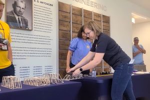 Pattie Mathieu, assistant professor of biomedical engineering at Marian University, places weights on students' bridges during the bridge competition.
