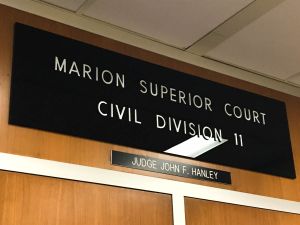 Patrick Gillen glances over his shoulder outside of the courtroom. He is speaking to a woman with light hair and a black and white shirt.