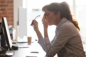 Frustrated woman at desk rubbing her forehead