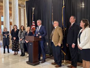 people on stage at a podium at the statehouse